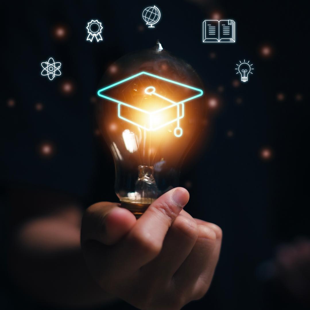 Concept graphic depicting a human hand holding a lit light bulb wearing a graduation cap