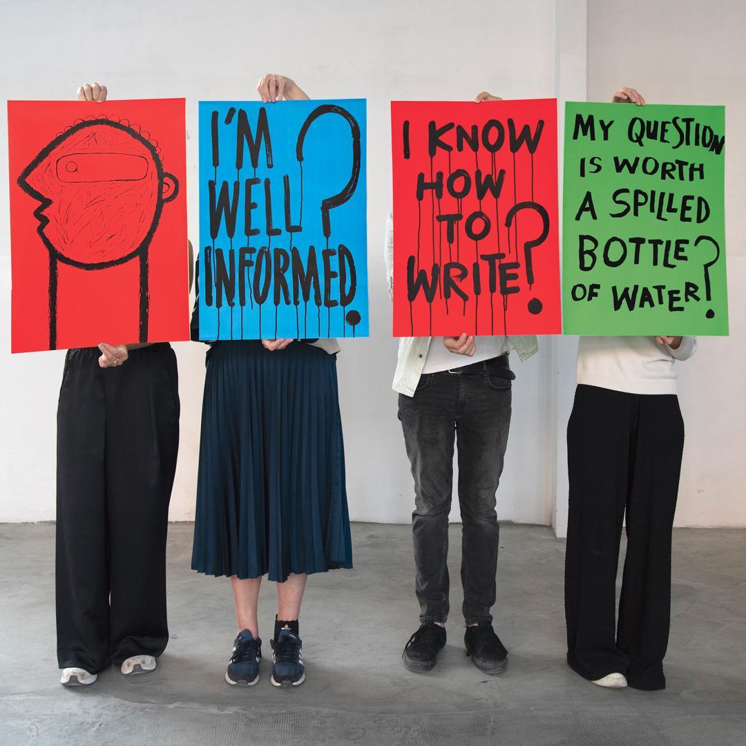 Four people in a line holding posters