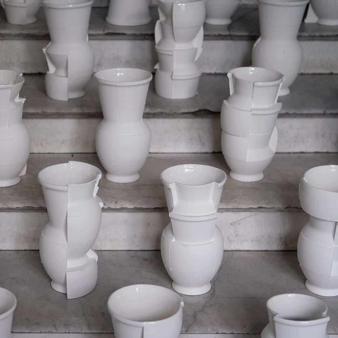 several white ceramic vases placed at random on marble steps