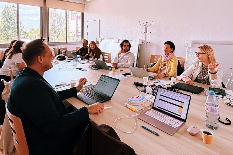 Academics sit at parallel tables and work together on a project
