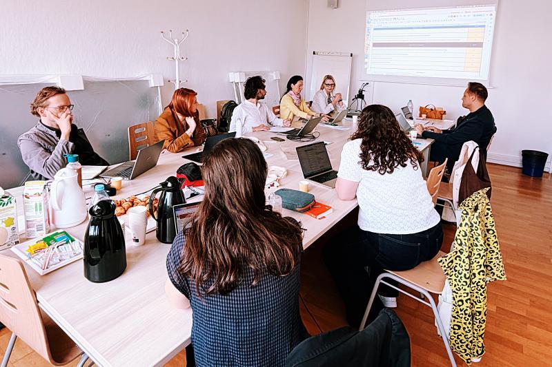 A group of academics sit at a table working on a project