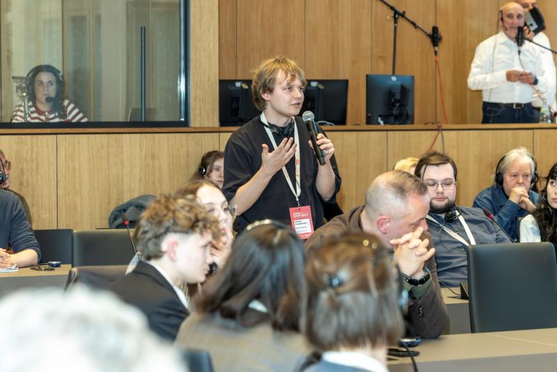 Male student holding a microphone asks a questions during a conference