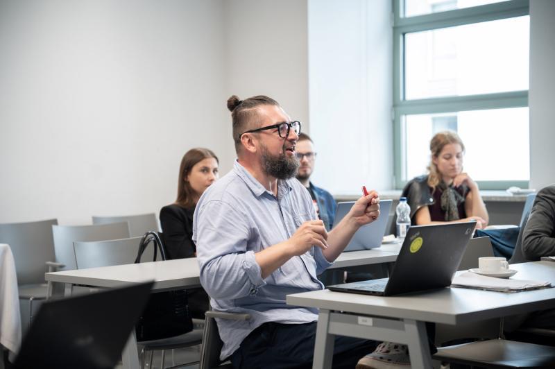 Prof. Mirosław Filiciak talks with doctoral students during workshop at USWPS
