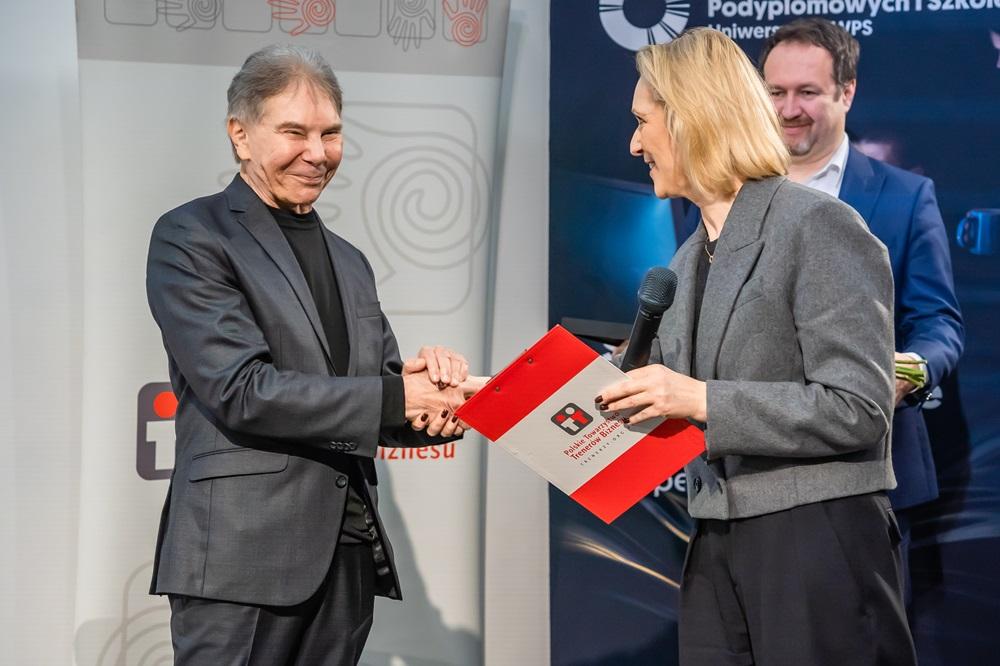 Professor Cialdini and a representative of the Polish Association of Business Trainers shake hands at the presentation of the award