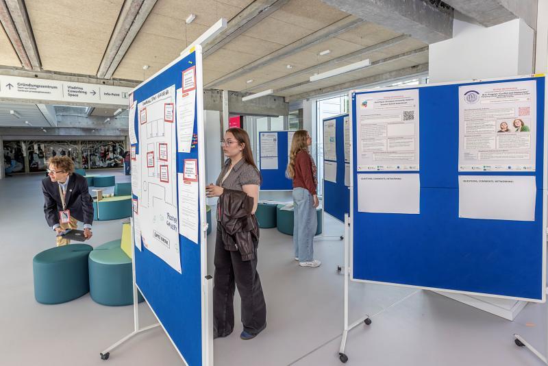 Two female students look at conference posters displayed in the hallway of the conference hall