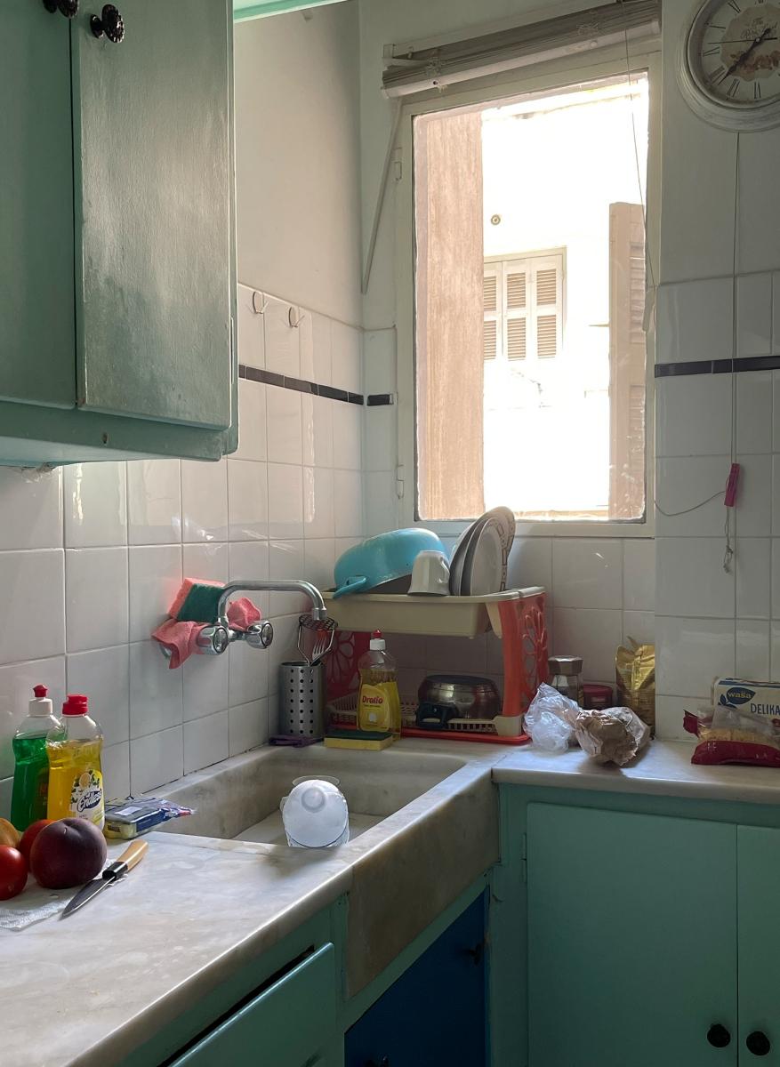 The interior of a small kitchen with a small window; typical kitchen accessories and dishes are on the countertop.