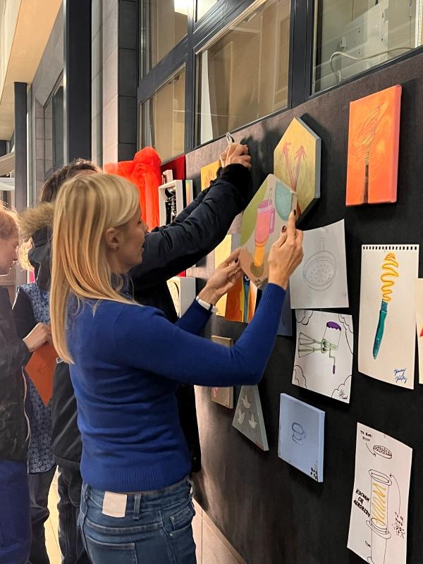 Participants at the opening of the “Inbetween” exhibition at SWPS University in Kraków hanging the works they created during the artistic happening