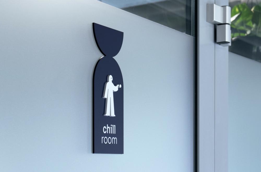 Dark blue sign on frosted glass featuring a white pictogram of a standing figure and the text "chill room".