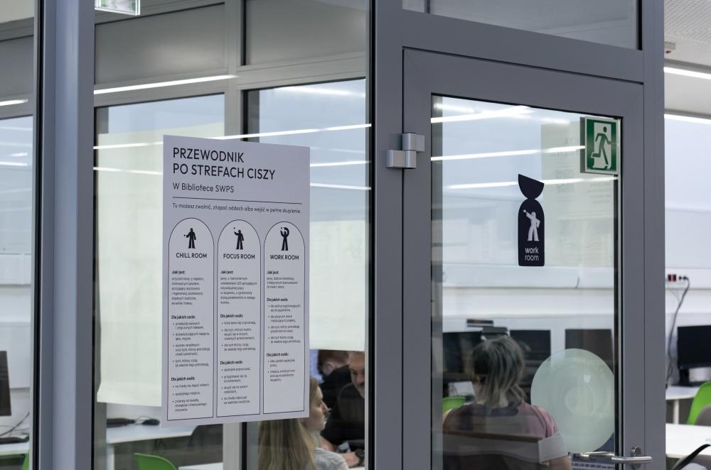 Quiet zones guide poster on a glass wall next to a black door sign with a pictogram and the text "work room" in a library.