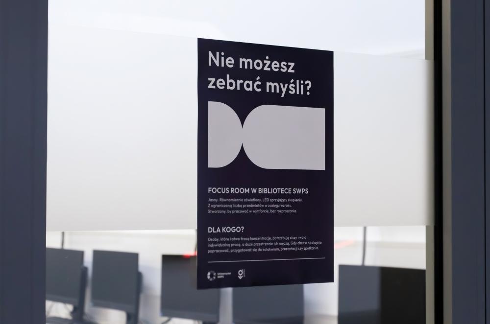 Black poster on a glass door with a headline in Polish