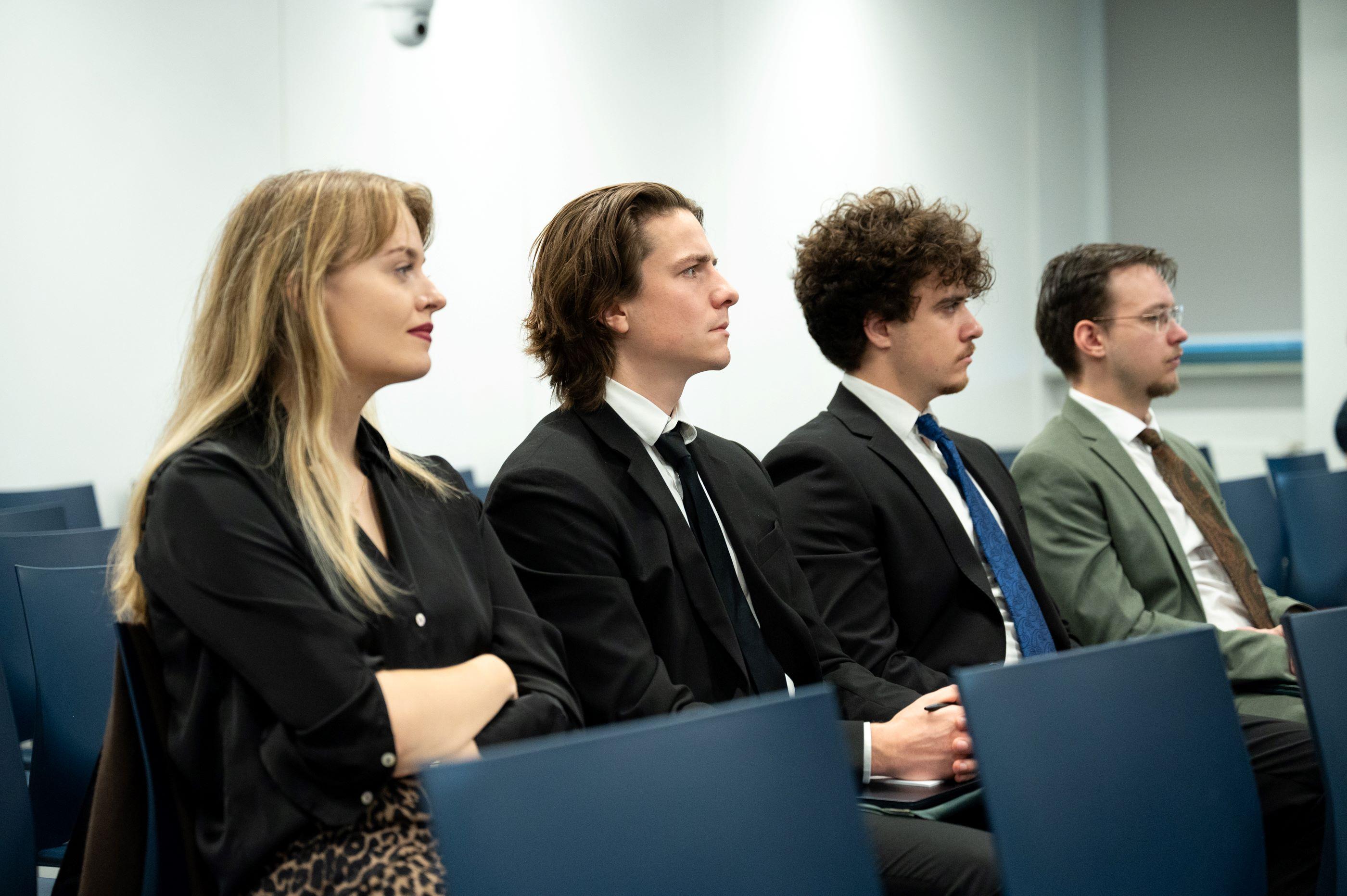 Two training participants sit in the lecture hall and smile at each other