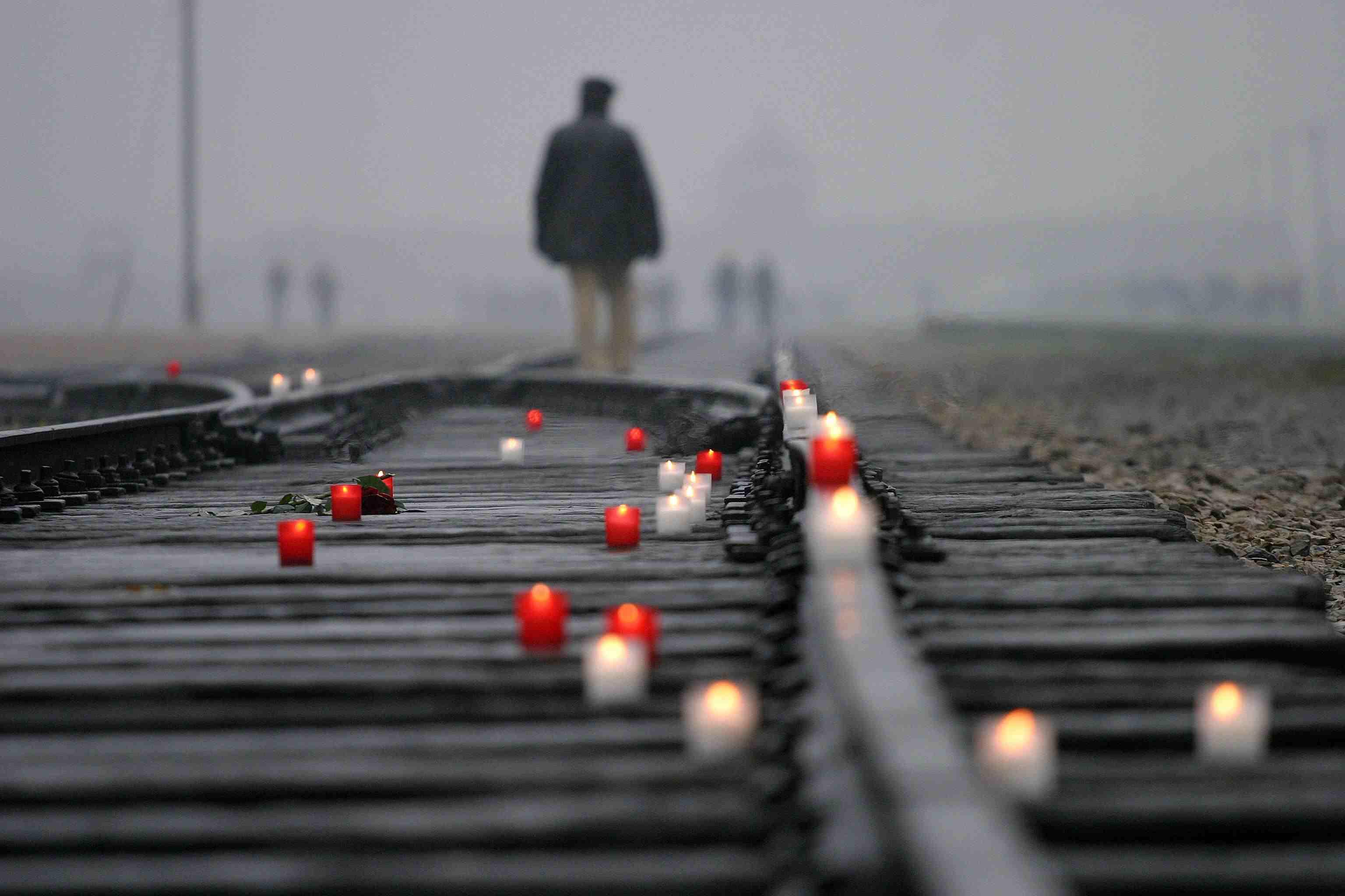 Candles burning on railway tracks leading to Auschwitz