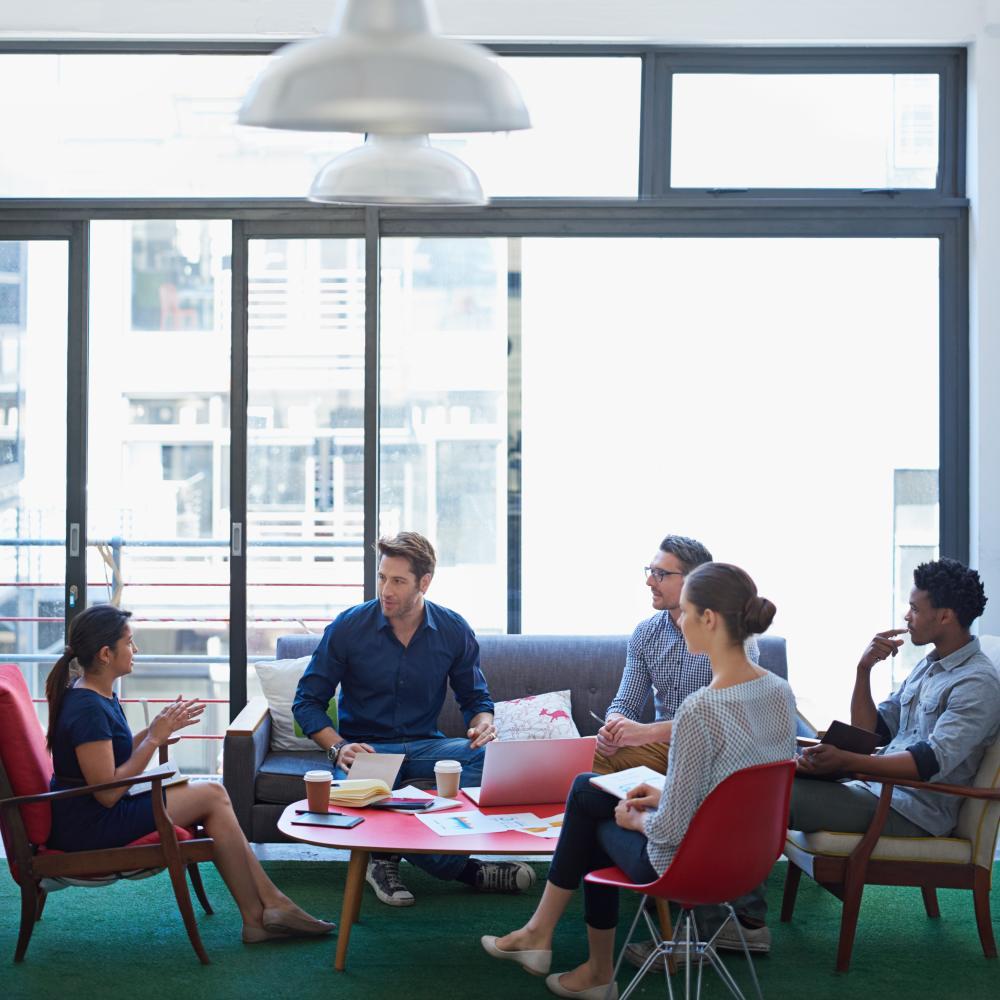 Mentor and students sit around a coffee table and talk