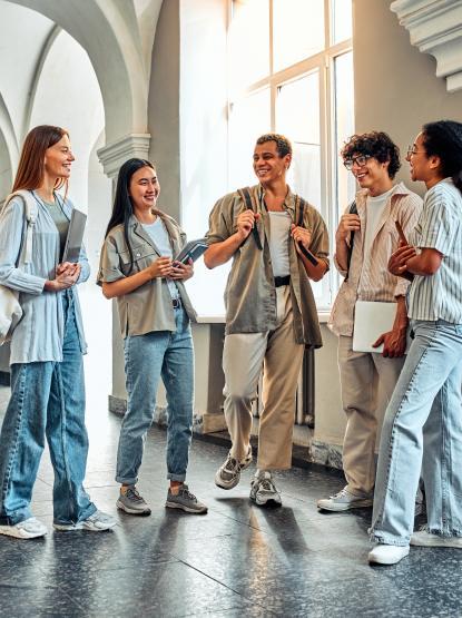 Group of international students stand and talk in a hallway of a university building