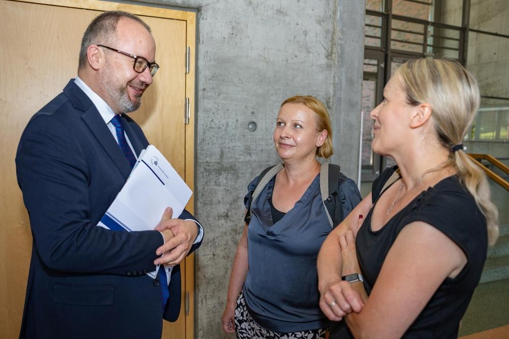 Adam Bodnar talks with two women and holds a diploma in his hands