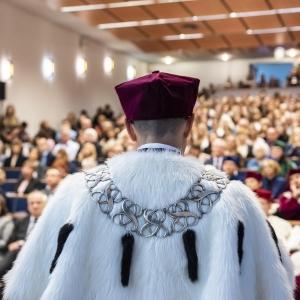 Photo of SWPS University rector standing in front of a full aula during an academic ceremony