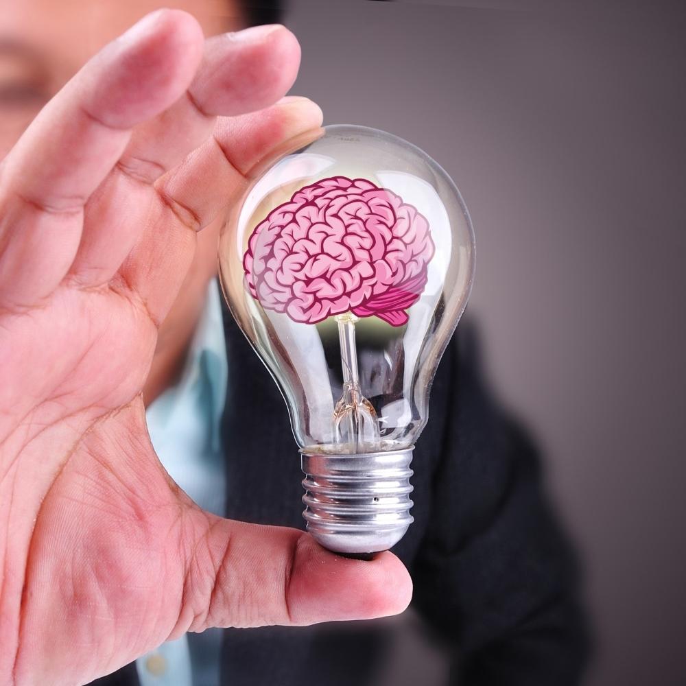 Hand holding a lightbulb with a symbol of brain inside