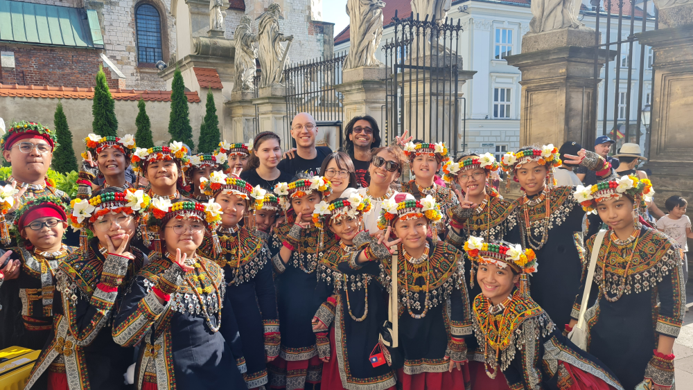 A group photo: Several SWPS University choristers with a large group of children in traditional Paiwan costumes